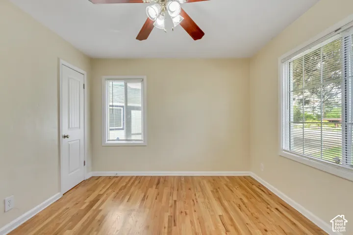 Hardwood flooring, painted walls, two windows, and a ceiling fan with integrated lighting