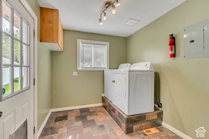 Built-in wood-finish cabinetry, window with horizontal blinds, overhead track lighting, and a multi-tone tile floor
