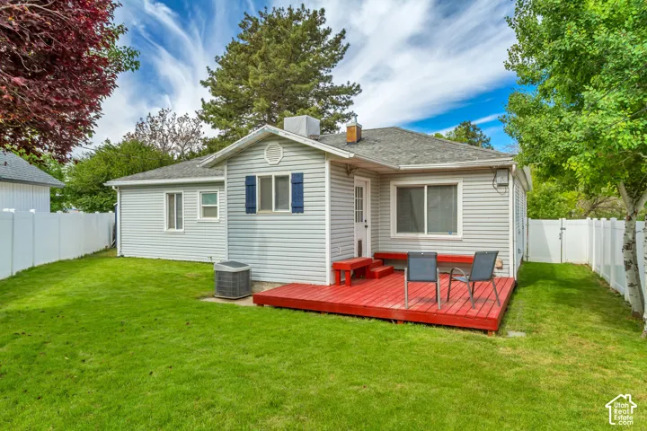 Expansive backyard with a manicured lawn, white privacy fencing, and mature trees