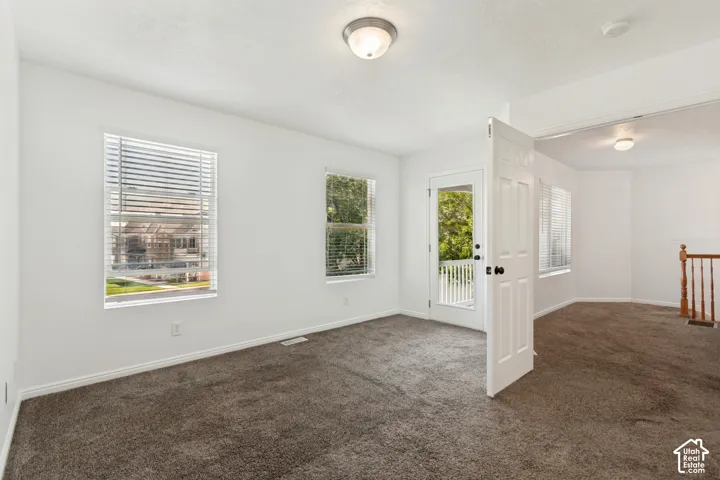 Spacious upper-level room featuring neutral carpeting, abundant natural light from multiple windows, and glass-paneled French doors providing access to additional living space