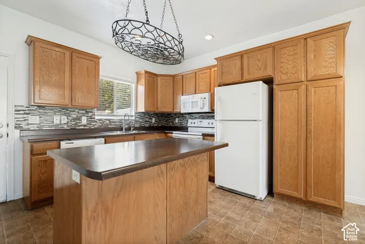 Kitchen featuring wood-finish cabinetry, a central island, a tile backsplash, and a built-in dishwasher