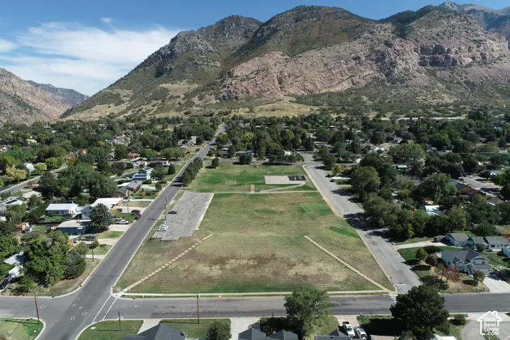 Expansive undeveloped lot featuring a large grassy area, adjacent paved parking, and surrounding residential streets