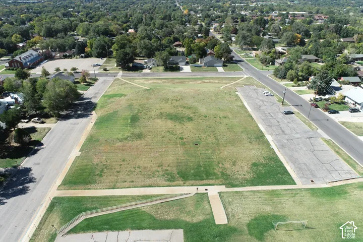 Expansive grass field with surrounding paved streets and mature trees