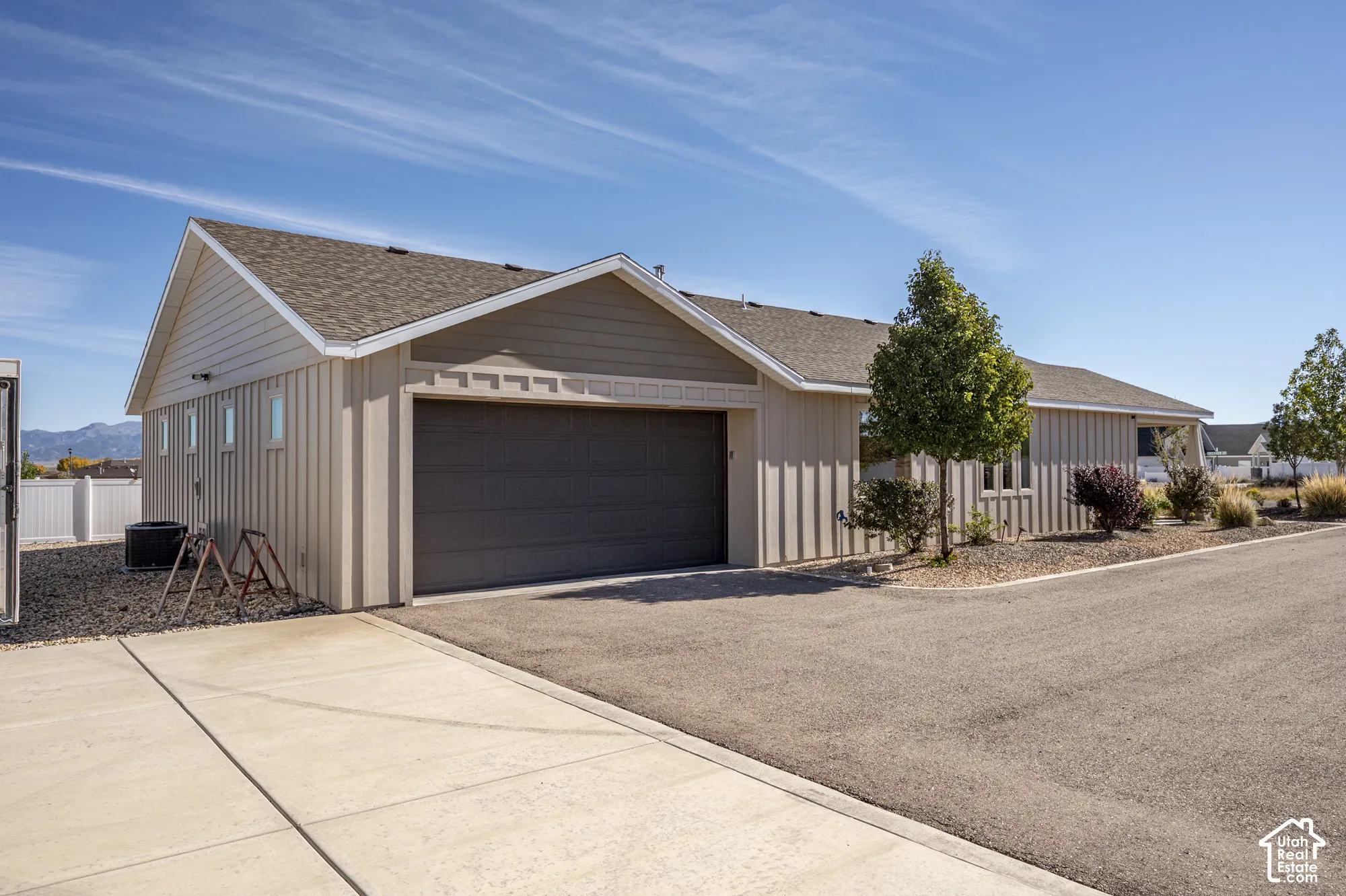 Single-story exterior with a gray garage door, light-colored vertical siding, and a shingled roof
