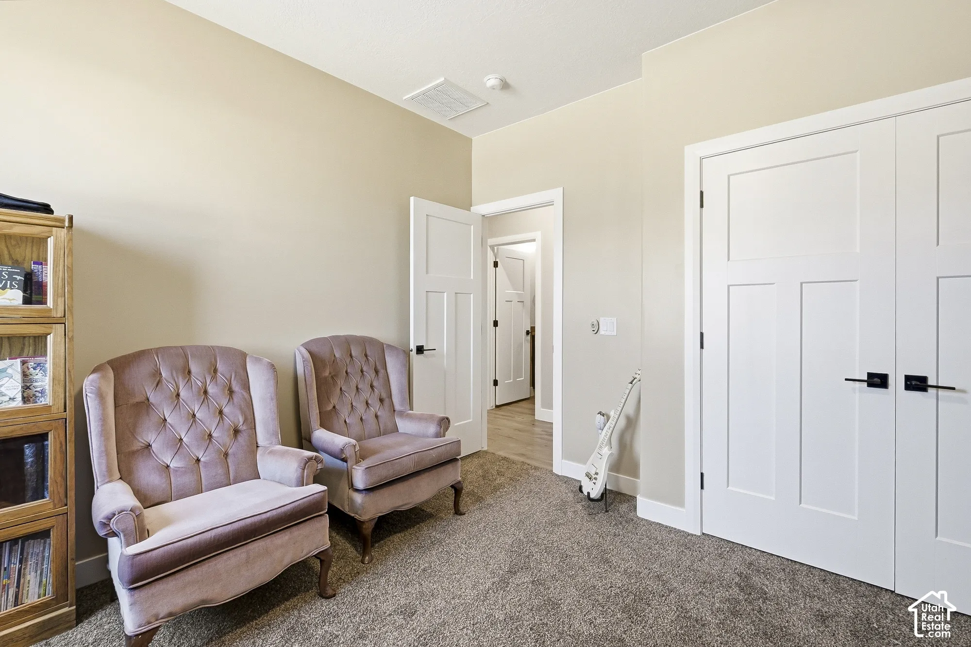 Neutral wall color, textured carpeting, white paneled doors, black hardware, and light wood-finish flooring