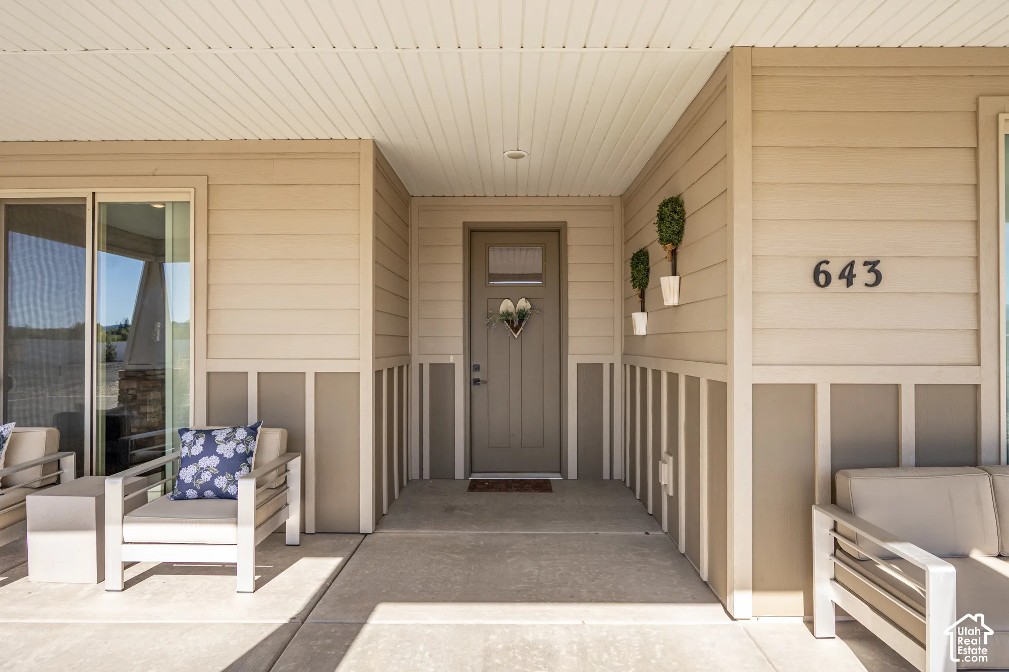 Covered concrete porch with horizontal siding and vertical paneling