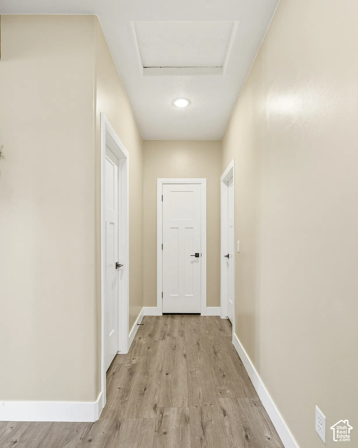Wood-finish flooring throughout, bright recessed lighting, white baseboards, and white doors with black hardware