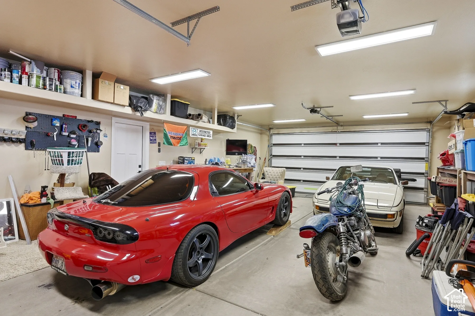 Spacious garage featuring a concrete floor, built-in shelving, overhead lighting, and an automatic garage door opener