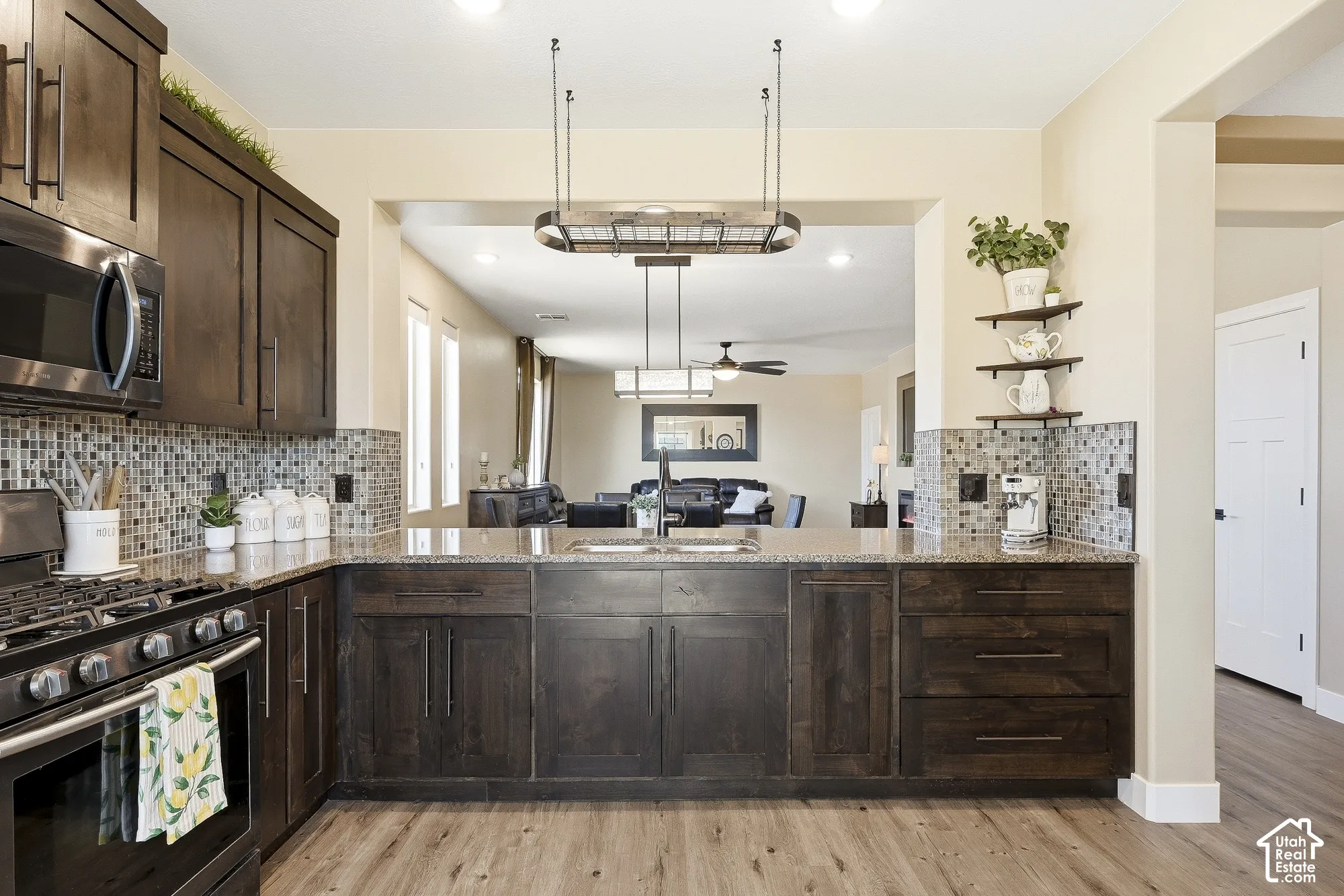Kitchen featuring dark wood-finish cabinetry, light-toned countertops, a mosaic tile backsplash, and wood-finish flooring