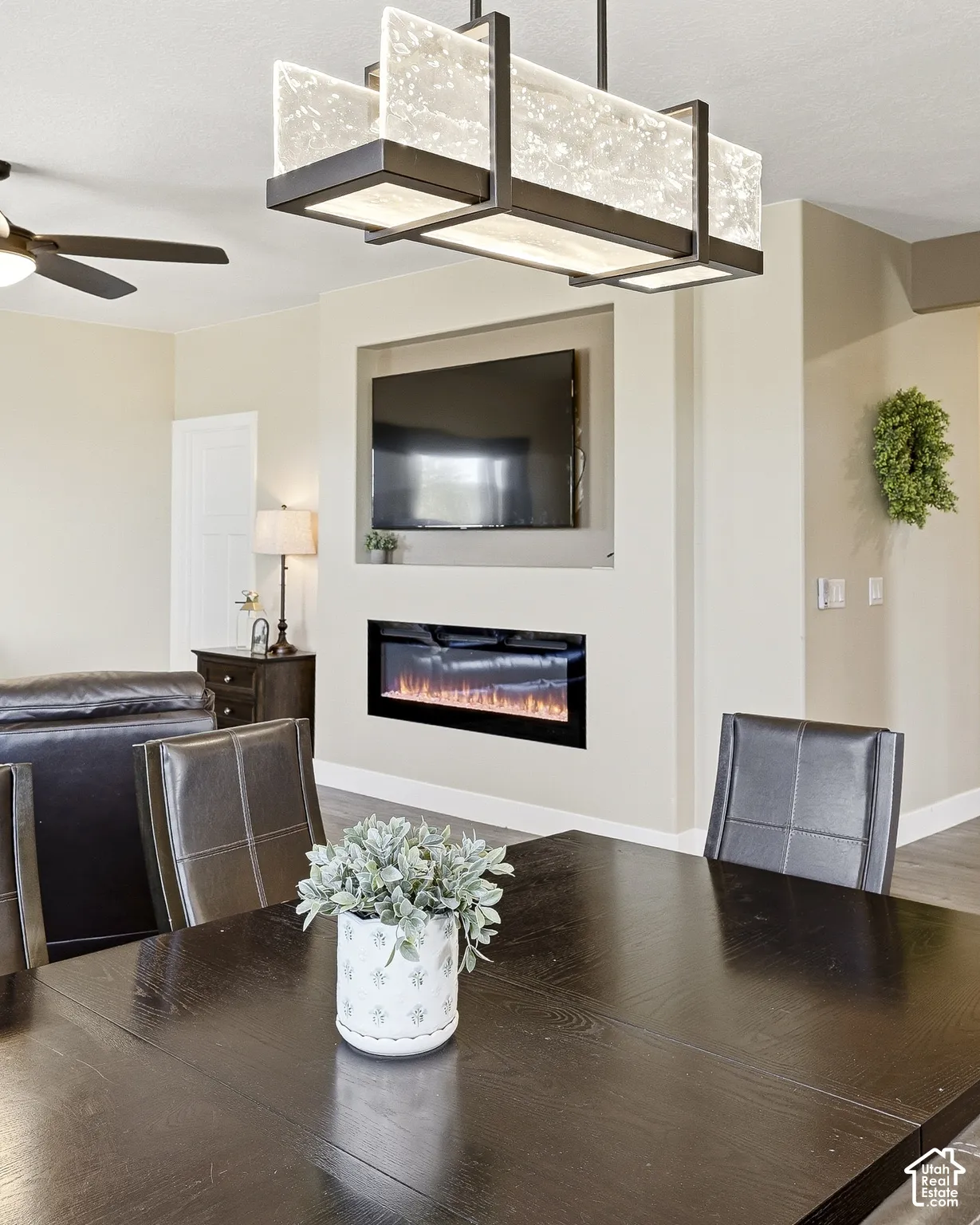 Built-in electric fireplace and media niche, overhead decorative lighting fixture, and wood-finish flooring