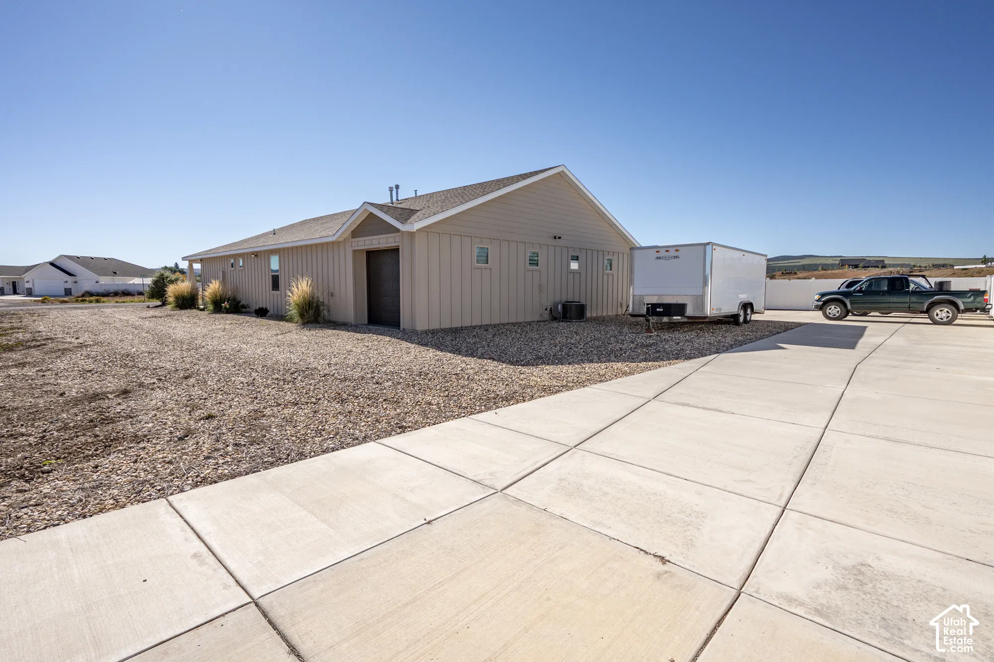 Exterior featuring vertical siding, a paved concrete driveway, a gravel landscape, and a side-entry garage