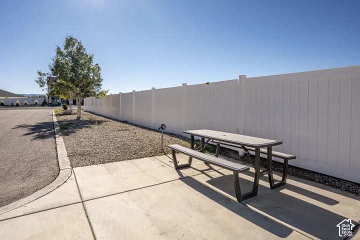 Paved patio area with a privacy fence, gravel landscaping, and a young tree
