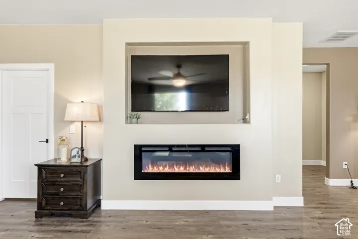 Built-in media niche, integrated electric fireplace, wood-finish flooring, white trim, and a white interior door