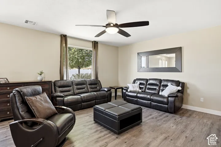 Wood-finish flooring throughout, ceiling fan with integrated lighting, and a large window with outdoor scenery