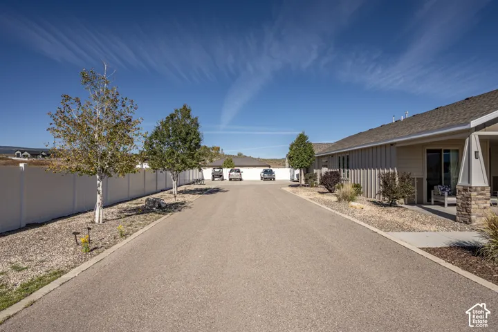 Paved driveway with gravel landscaping, white privacy fencing, and exterior siding with stone accents
