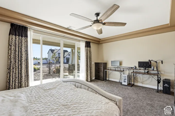 Sliding glass door to outdoor space, ceiling fan with light fixture, tray ceiling, neutral wall color, and carpeted flooring