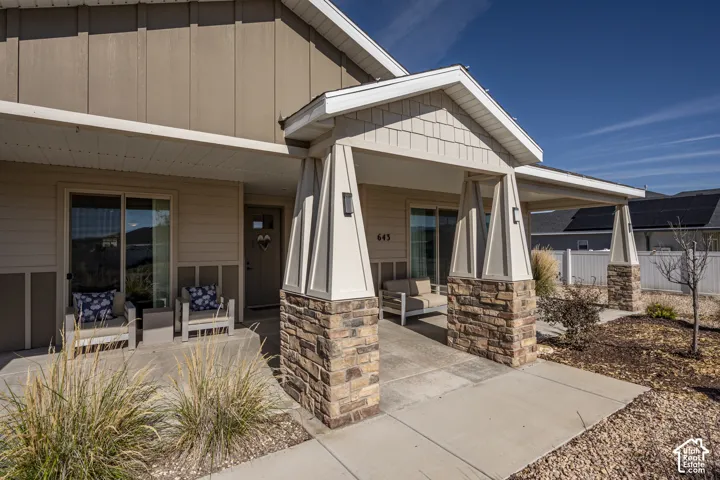 Stone veneer accents on porch columns, covered front porch, horizontal siding, vertical board and batten siding, and architectural shingles