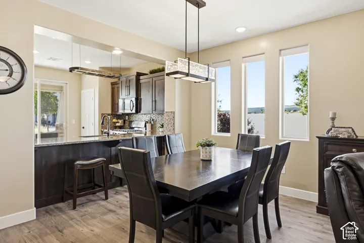 Kitchen with wood-finish flooring, dark wood cabinetry, and a mosaic tile backsplash