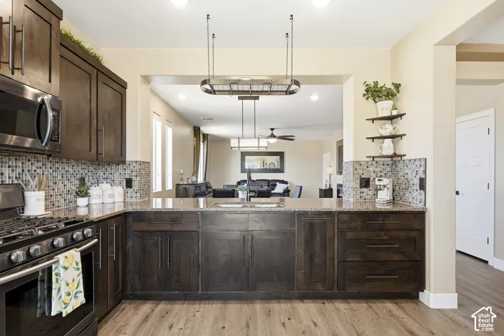 Kitchen featuring dark wood-finish cabinetry, light-toned countertops, a mosaic tile backsplash, and wood-finish flooring