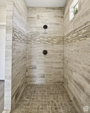 Tiled shower stall with dual shower heads, horizontal mosaic tile accent, and a built-in window