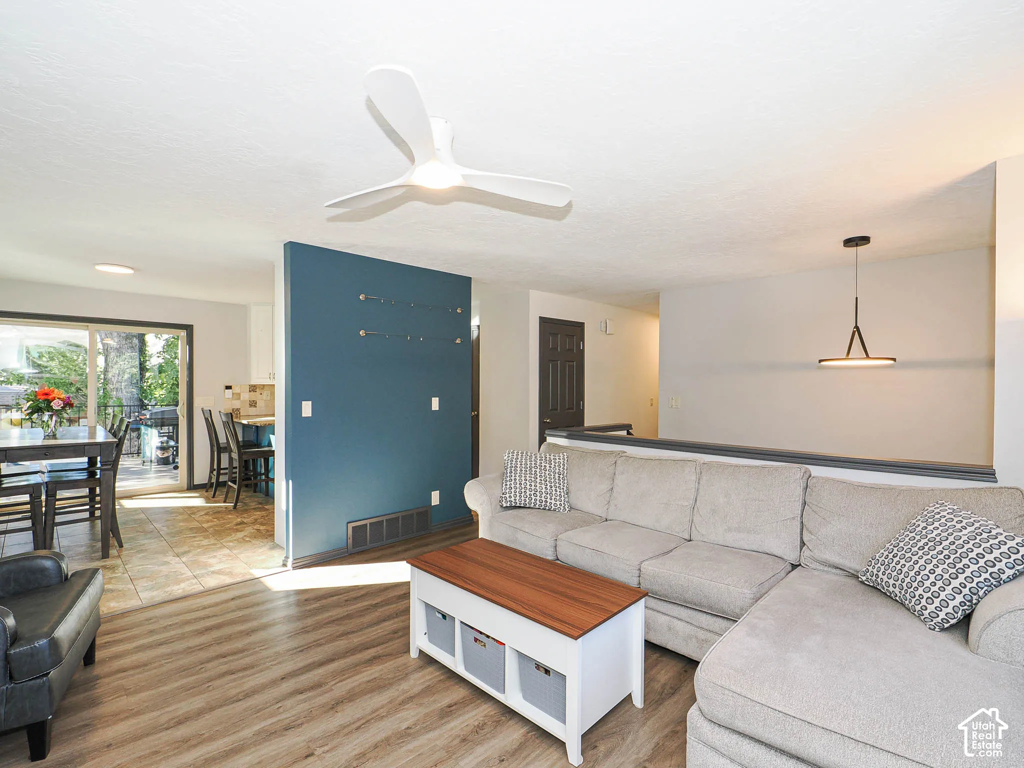 Wood-finish flooring, contemporary ceiling fan, sliding glass door, tiled kitchen flooring, and modern pendant light fixture