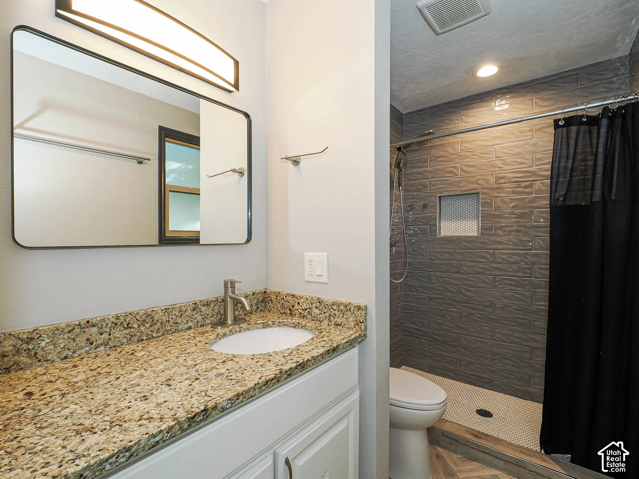 Vanity with a speckled countertop, undermount sink, and brushed nickel faucet