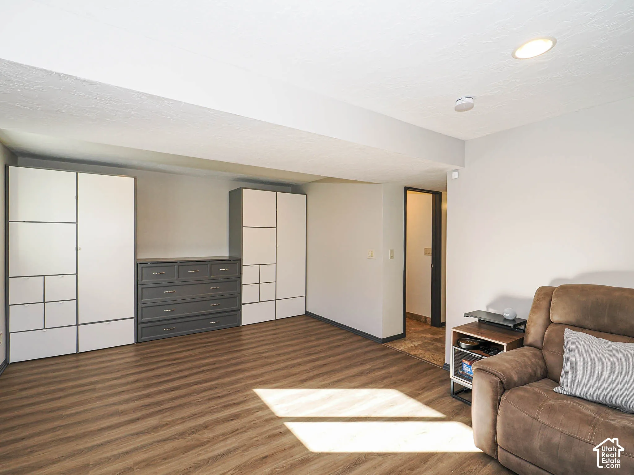 Wood-finish flooring, recessed ceiling lighting, light gray wall paint, built-in storage cabinetry, and a built-in dresser with drawers
