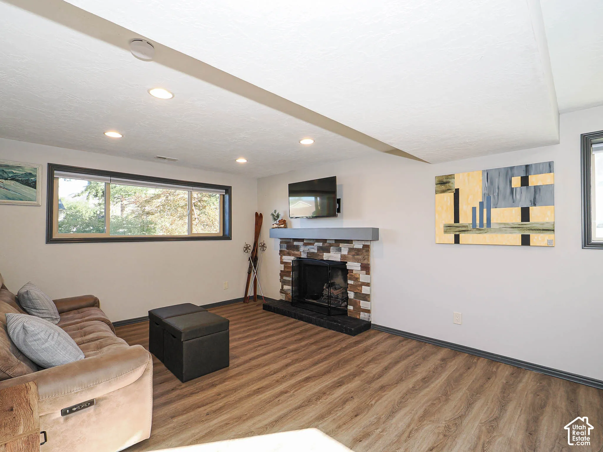 Wood-finish flooring with a stone-clad fireplace and a contrasting mantel