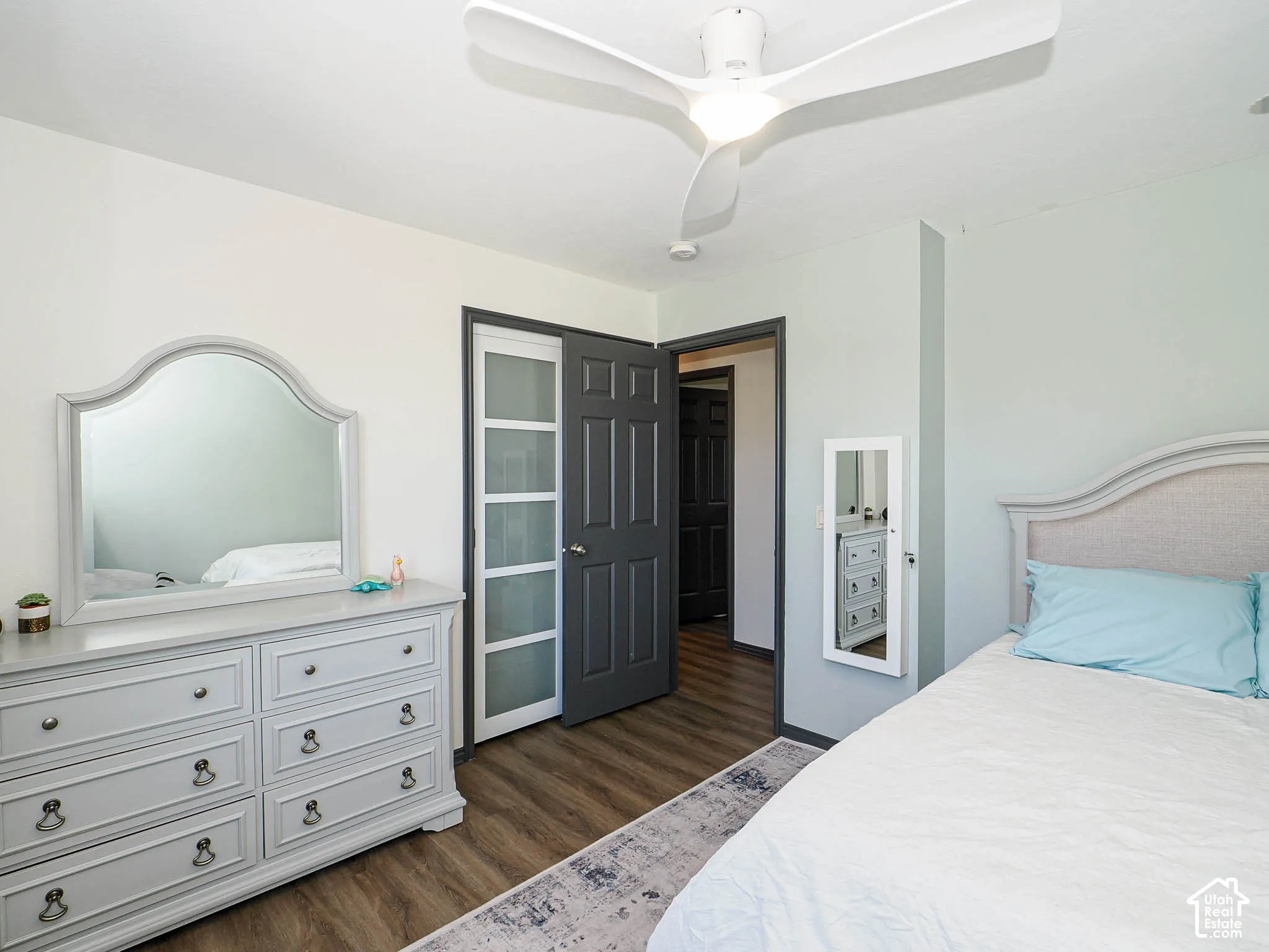 Wood-finish flooring, white ceiling fan, and painted interior doors
