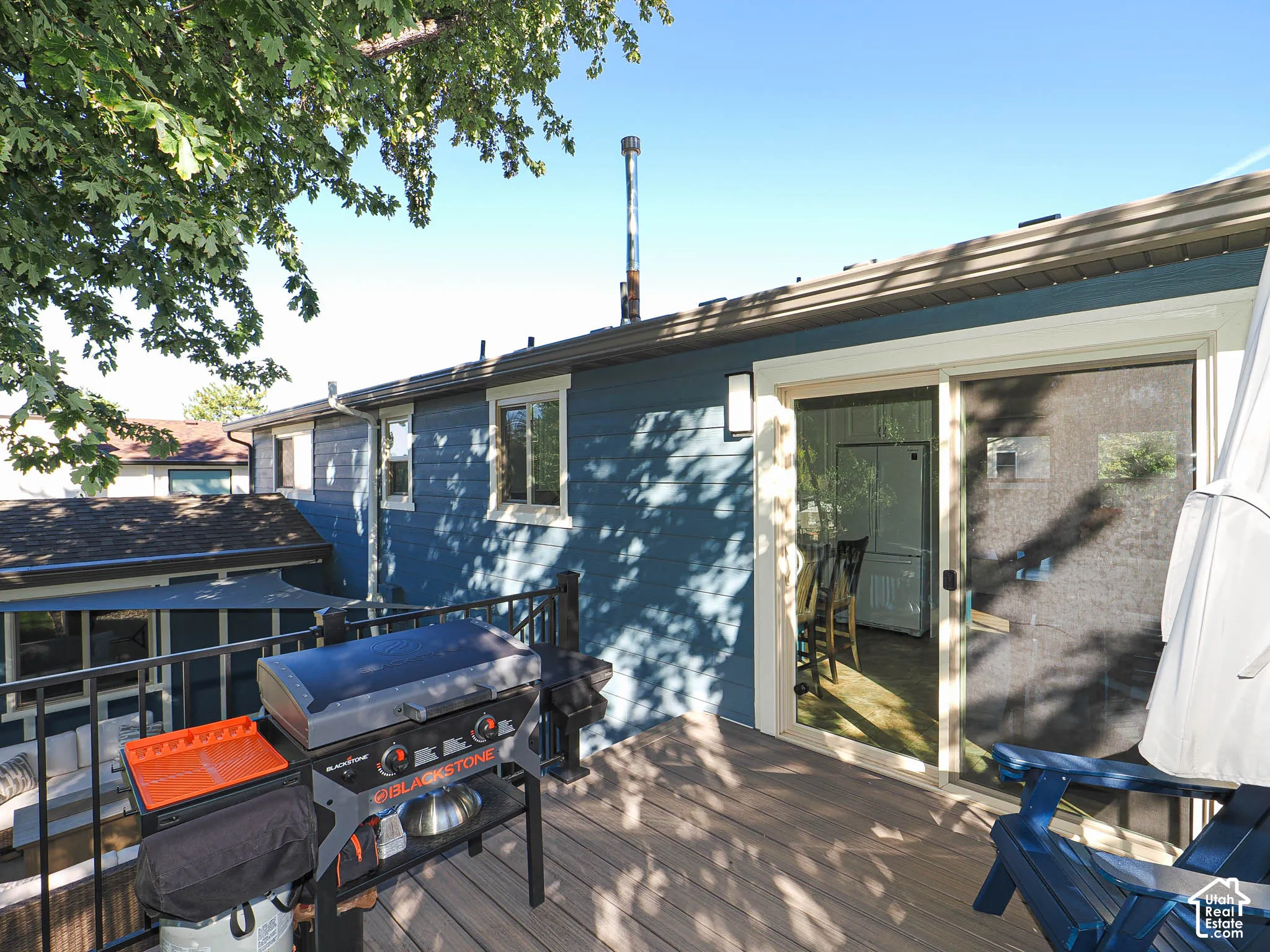 Deck with wood-finish flooring, black metal railing, blue exterior siding, and sliding glass door