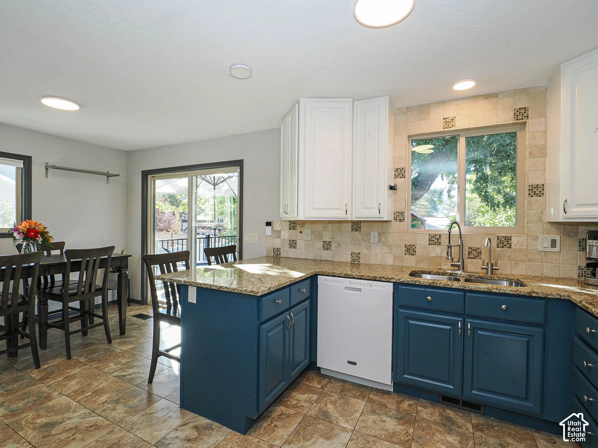 Kitchen featuring blue base cabinetry, white upper cabinetry, granite countertops, tile flooring, and a tiled backsplash
