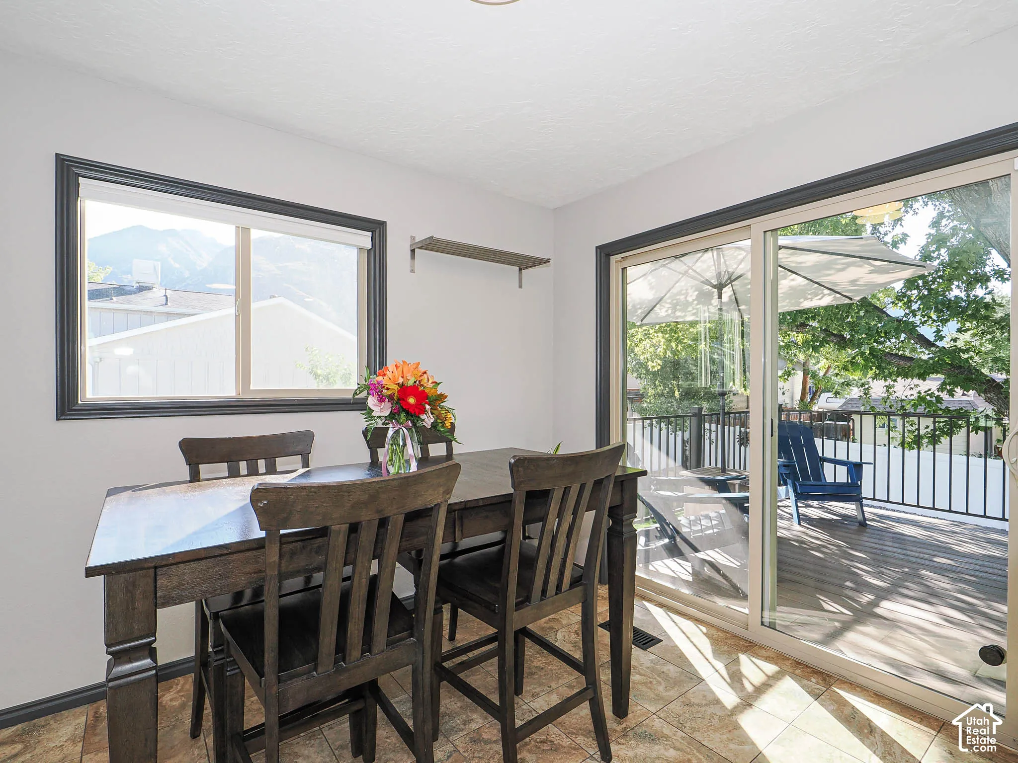 Spacious room with a large window and sliding glass door, featuring tile flooring, white walls, and dark trim