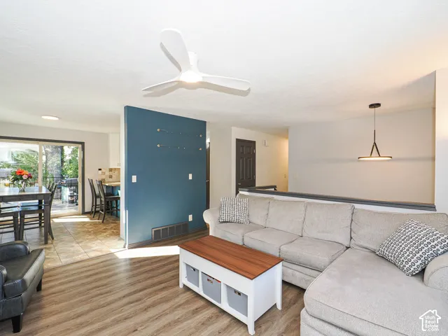 Wood-finish flooring, contemporary ceiling fan, sliding glass door, tiled kitchen flooring, and modern pendant light fixture