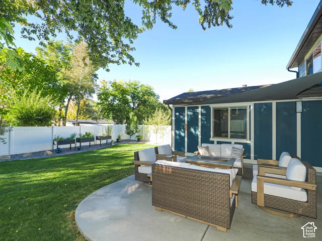 Expansive backyard featuring a concrete patio, a manicured lawn, and raised garden beds