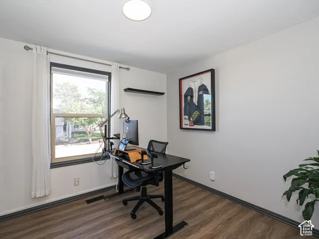 Wood-finish flooring, single window with dark trim, recessed ceiling light, and a wall-mounted shelf