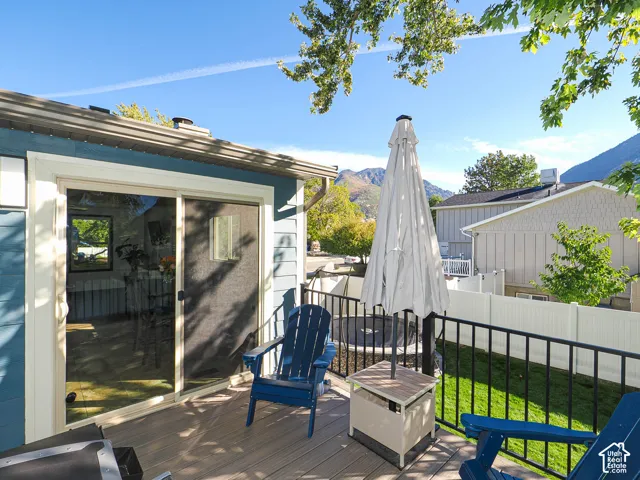 Deck with wood-finish flooring, black metal railing, and a sliding glass door