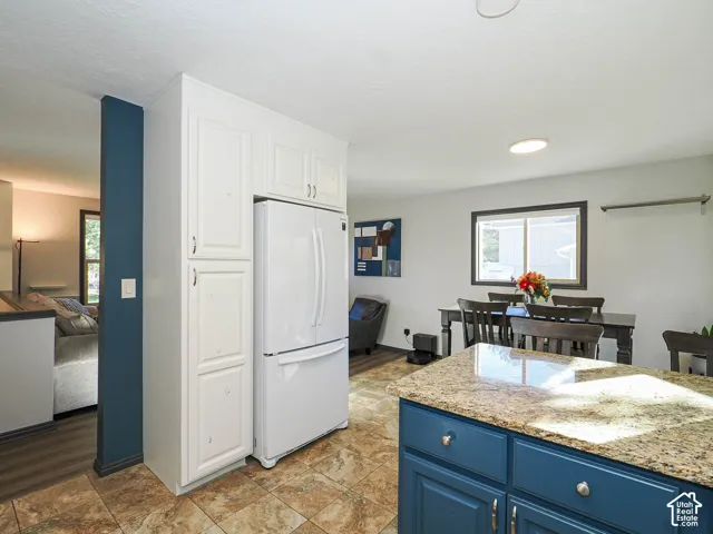 Built-in white cabinetry, French door refrigerator, tiled flooring, granite countertop, and blue lower cabinetry