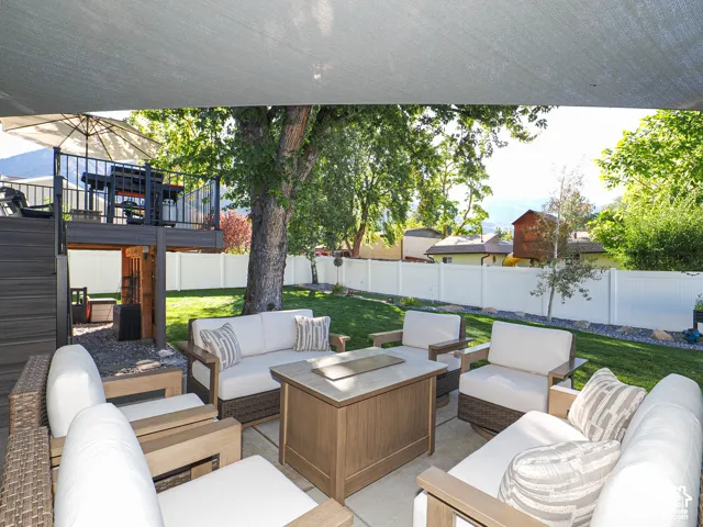Expansive backyard featuring a green lawn, white privacy fencing, and mature trees
