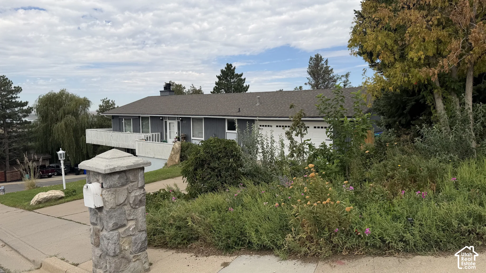 Cantilevered balcony, attached garage, and stone-clad mailbox pillar