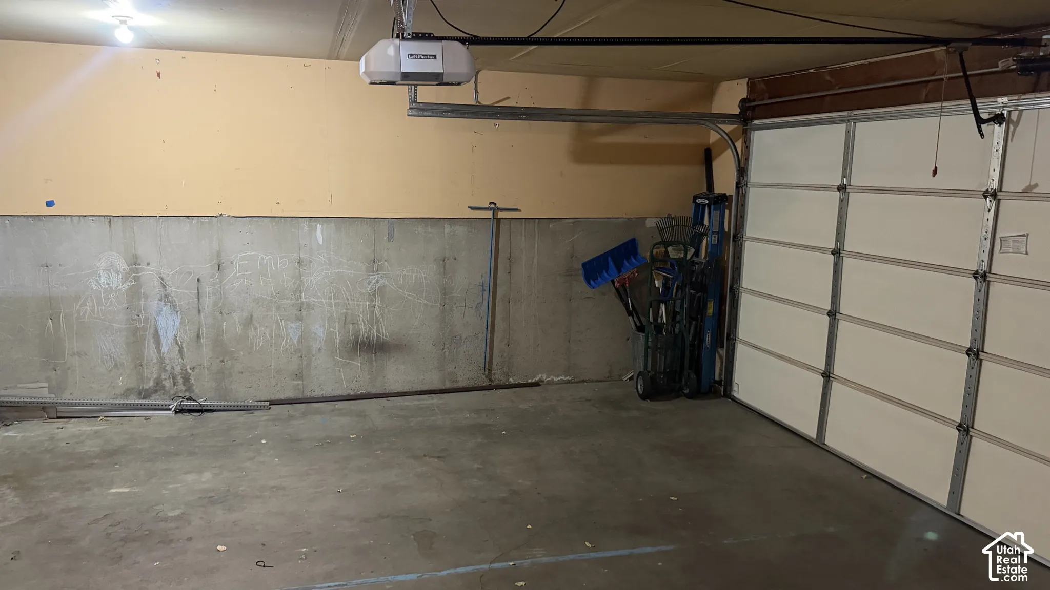 Concrete flooring garage with an automatic garage door opener and overhead lighting