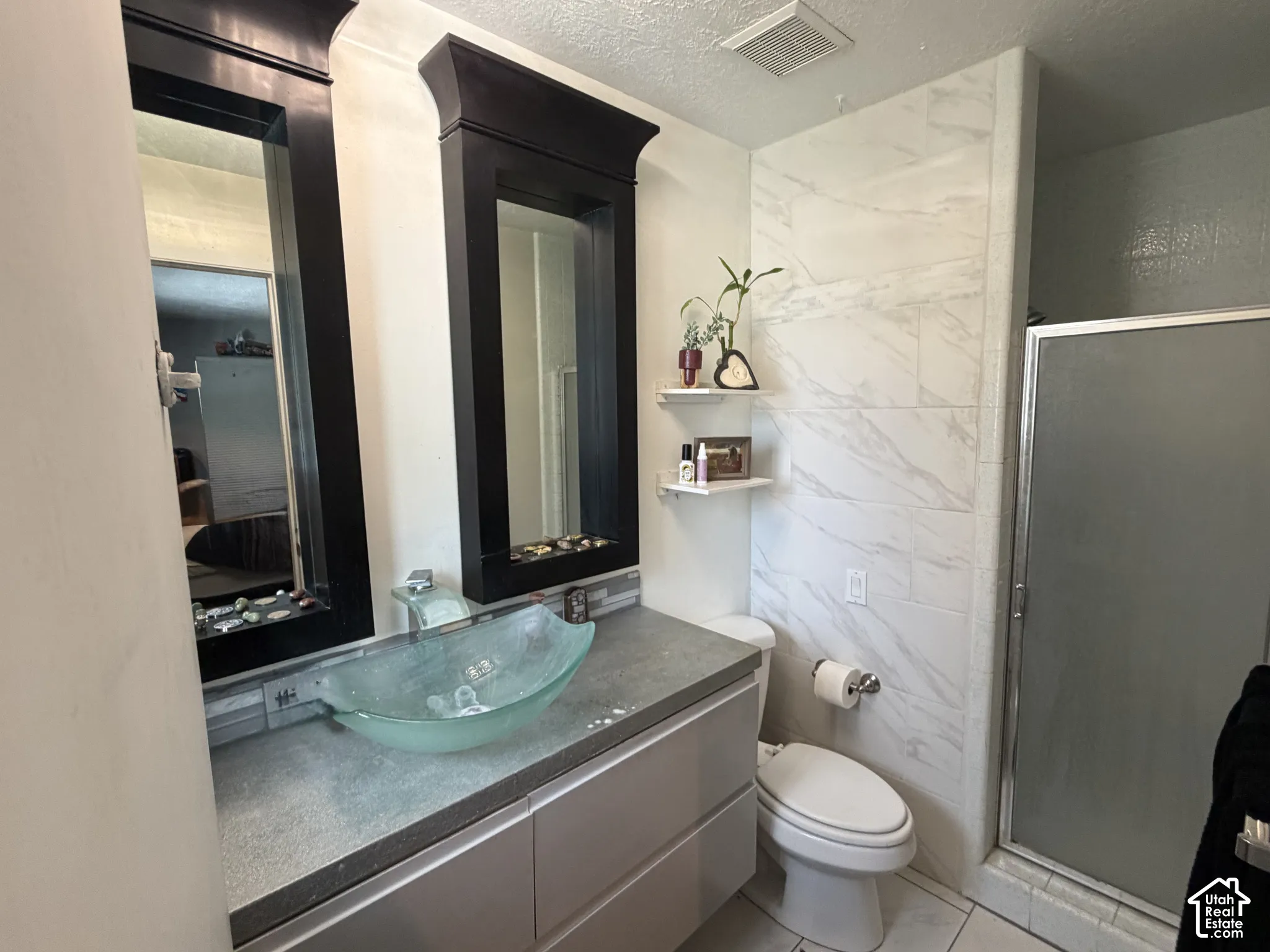 Bathroom 1- Dual framed mirrors, vessel sink, vanity with storage and glass-enclosed shower
