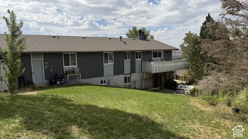 Spacious residential home featuring a modern dark-finish exterior with multiple entry points, expansive manicured lawn with mature landscaping, and a multi-level deck structure providing outdoor living space