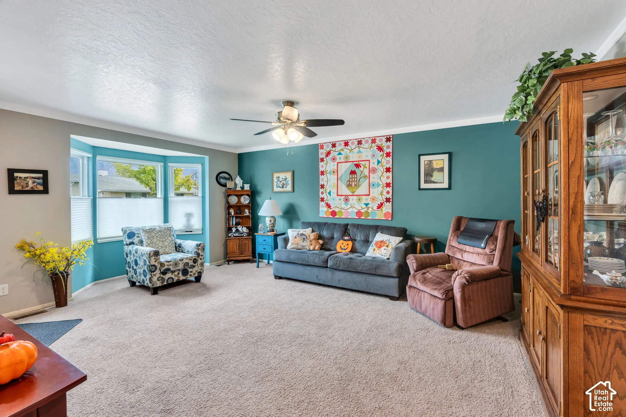 Bay window with blinds, ceiling fan, and crown molding