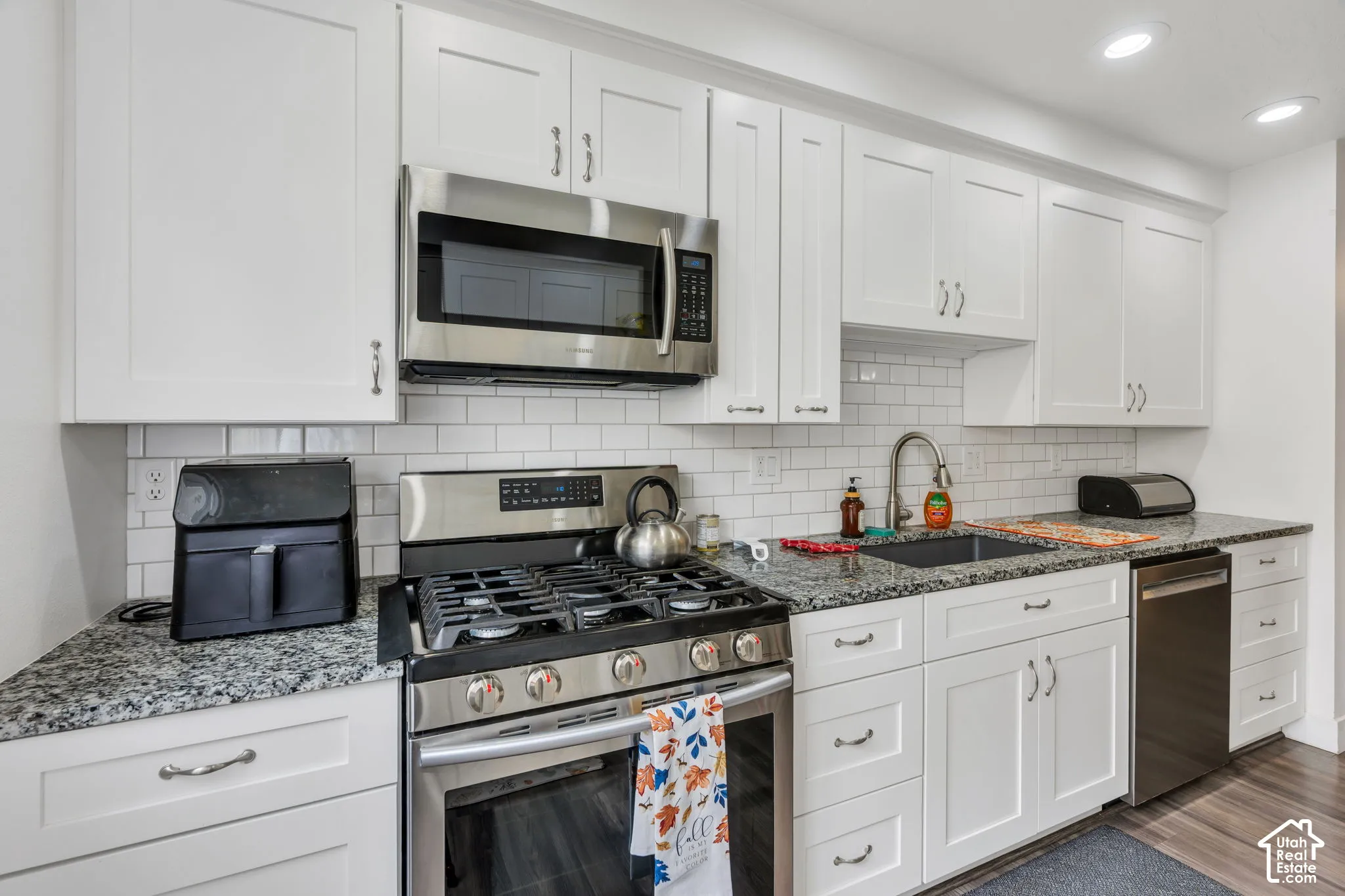 White shaker cabinetry, stainless steel appliances, granite countertops, subway tile backsplash, and recessed lighting