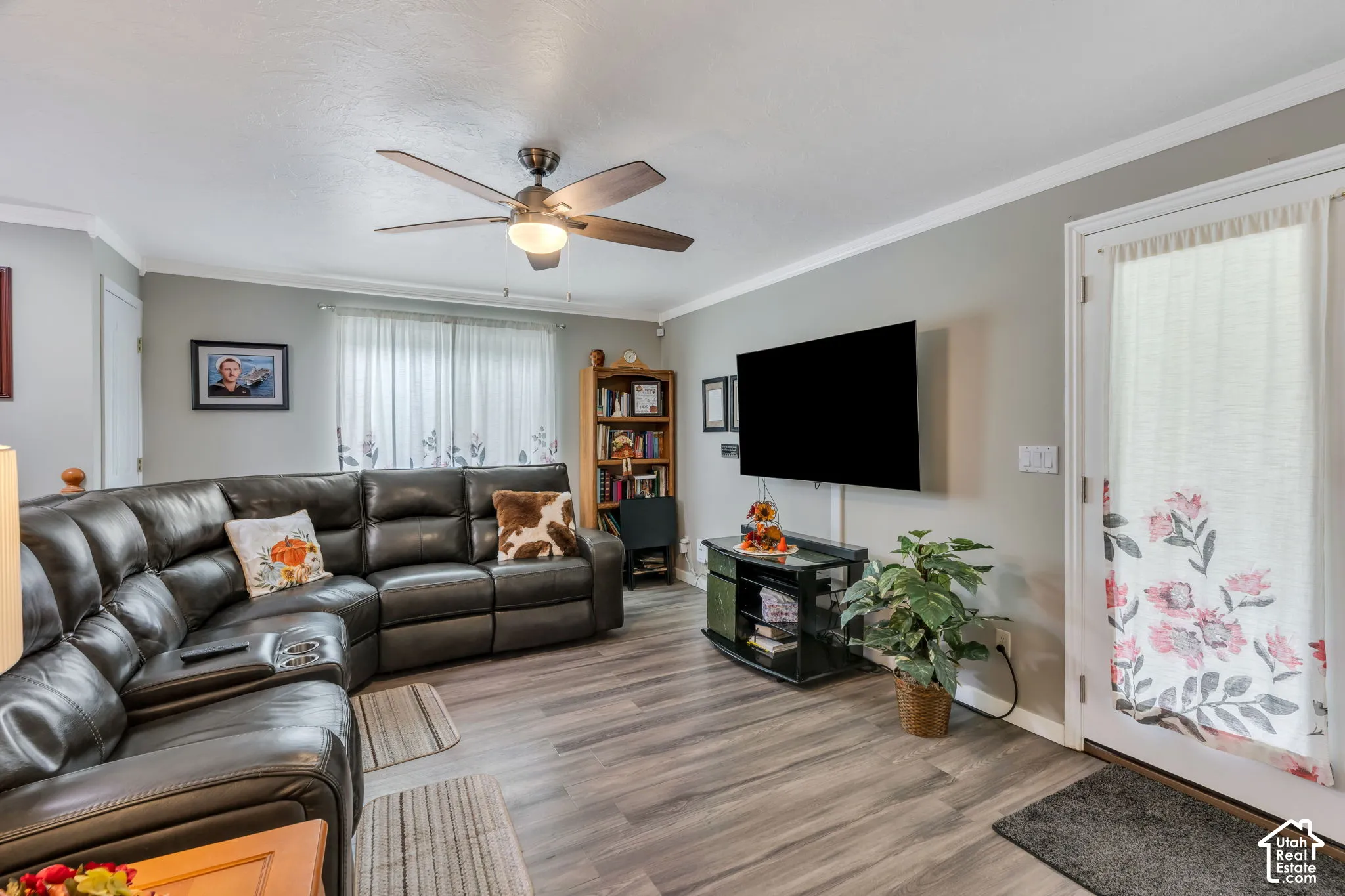 Wood-finish flooring, ceiling fan with integrated lighting, and white trim
