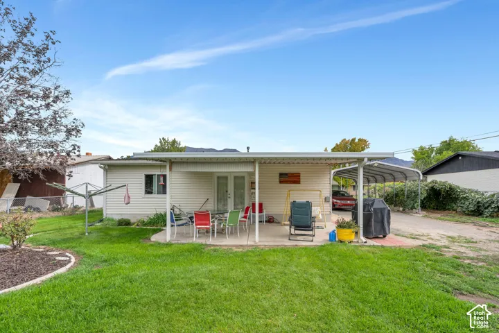 Expansive backyard featuring a covered patio, dual French patio doors, and a covered carport