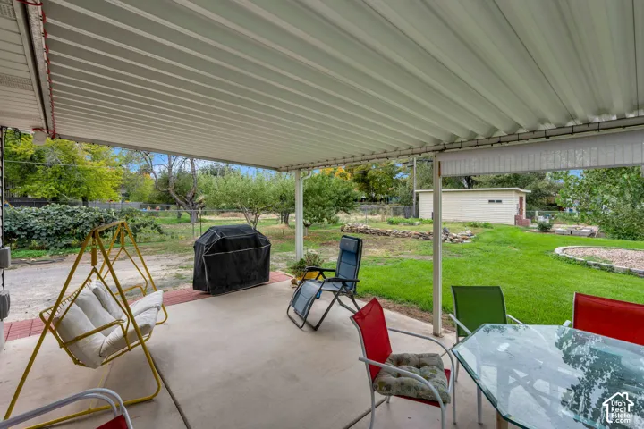 Covered patio with concrete flooring, supported by white metal posts