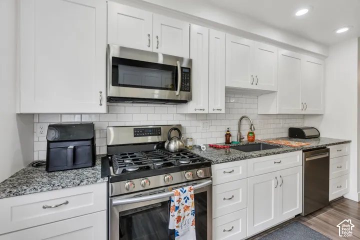 White shaker cabinetry, stainless steel appliances, granite countertops, subway tile backsplash, and recessed lighting