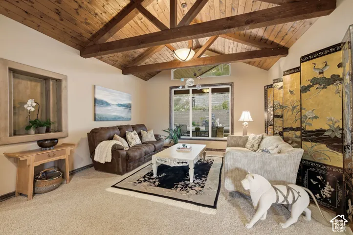 Vaulted wood-plank ceiling with exposed beams, recessed wall niche, expansive window, and neutral carpeting