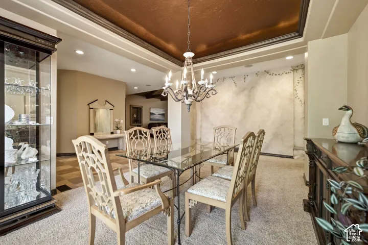 Tray ceiling with a textured finish, decorative wall treatment, recessed lighting, and an ornate chandelier